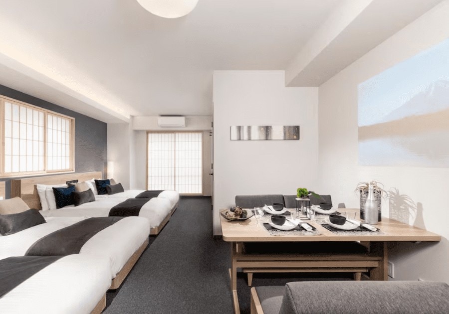 A theater-type hotel room with three beds, with wooden table across the beds perfect for families. Located in Ginza.
