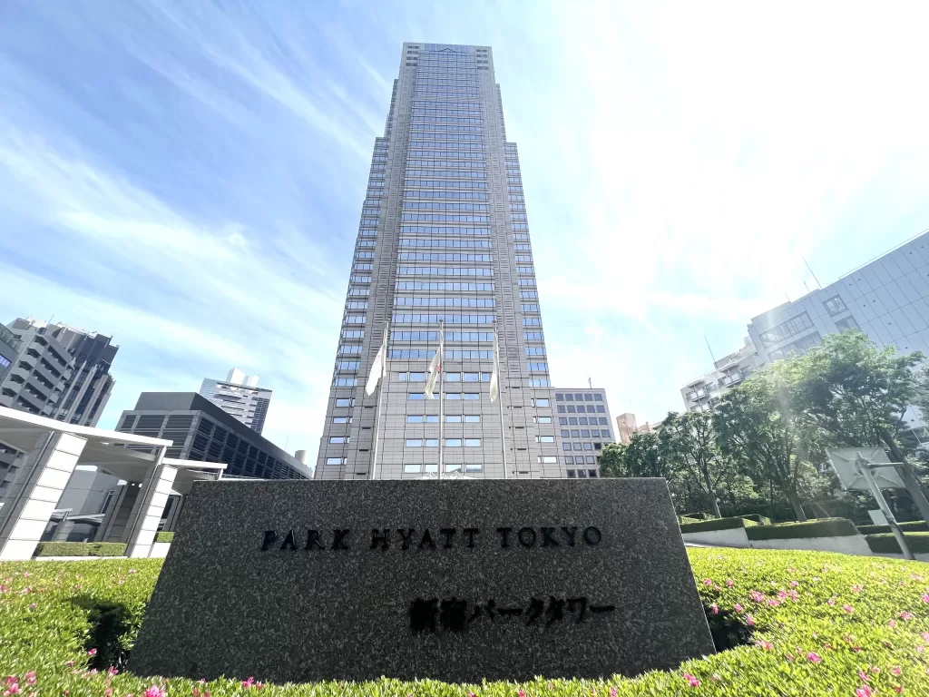 A tall building with three flags and a name "PARK HYATT TOKYO" with some Japanese texts below it. This is the Best Luxury Hotel in Shinjuku.